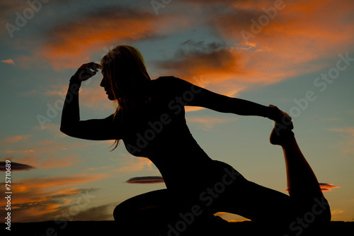 silhouette of a woman on knees hold one foot up