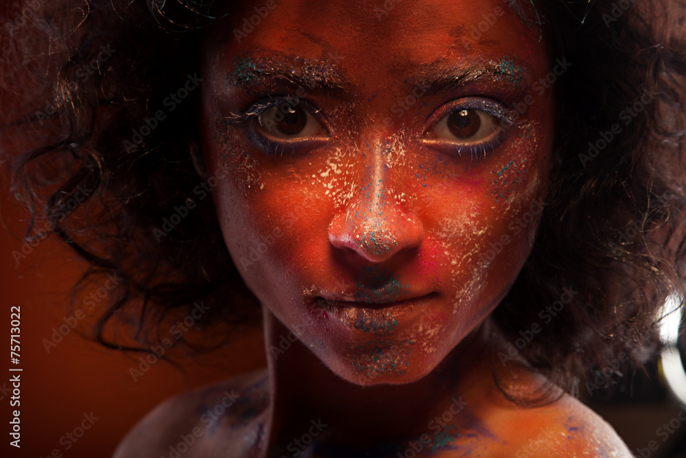 young woman with creative red face-art and afro hair young woman with creative red face-art and afro hair