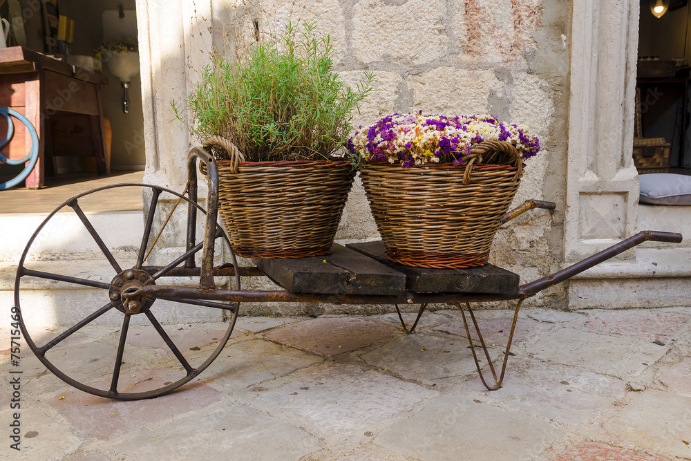 old wheelbarrow with baskets of flowers