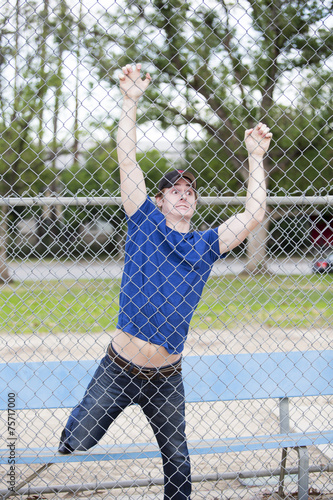 young man hanging on fence at sportsfield