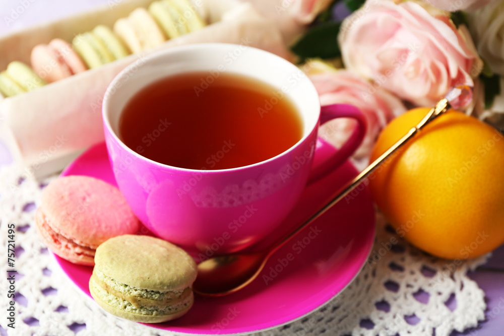 Colorful macaroons with cup of tea on wooden background Colorful macaroons with cup of tea on wooden background
