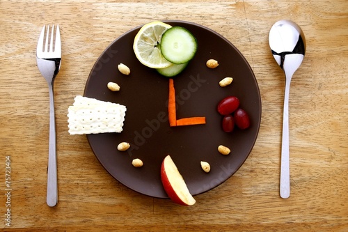 Fruits, veggies, nuts, crackers on a plate arranged like a clock photo