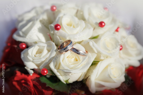 Gold wedding rings on a bouquet of beige roses