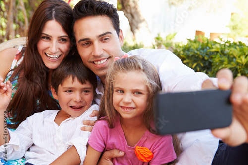 Family Sitting On Seat In Garden At Home Taking Selfie