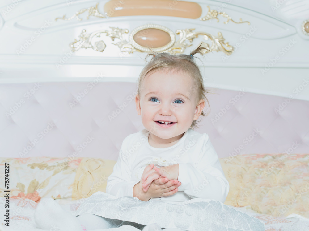Small caucasian child girl sitting on the bed at home Small caucasian child girl sitting on the bed at home