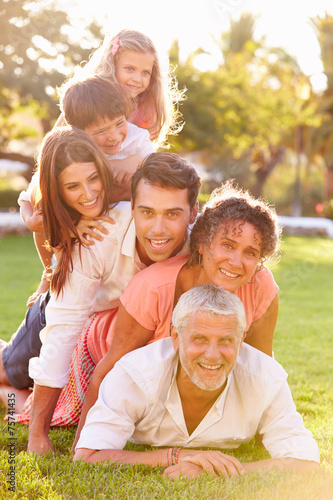 Multi Generation Family Lying In Pile Up On Grass Together