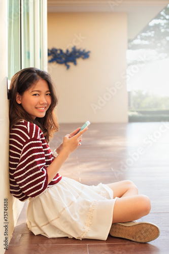 portrait of beautiful teen and mobile phone in hand sitting at h photo