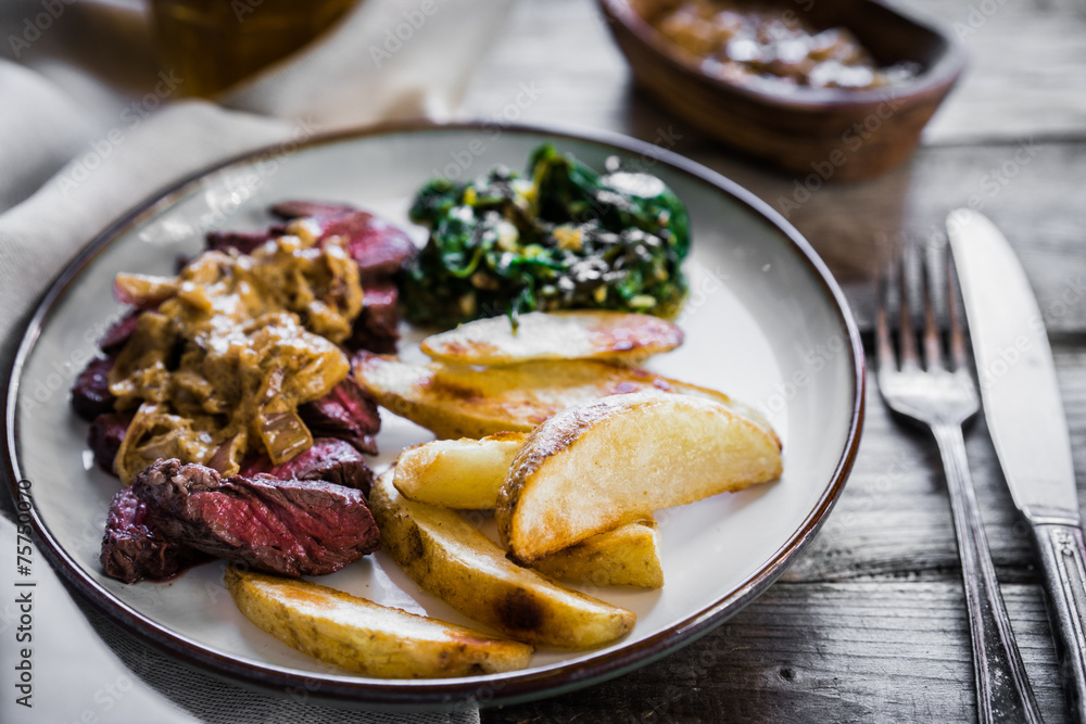 Steak with baked botatoes and green salad on wooden background