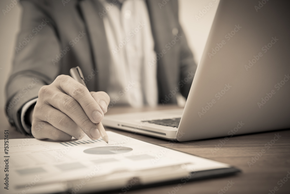 Fototapeta premium Businessman analyzing investment charts with laptop. Accounting