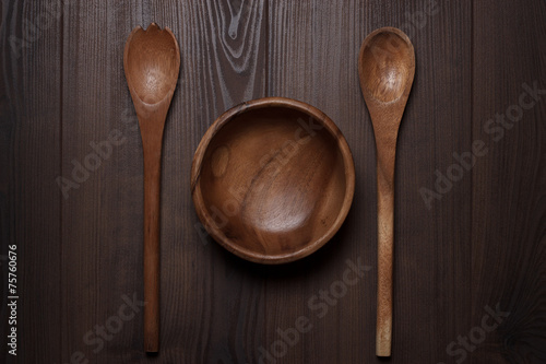 wooden salad bowl and two spoons on the brown table