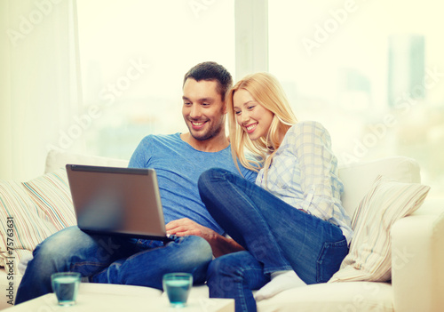 smiling happy couple with laptop at home