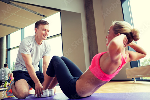 woman with personal trainer doing sit ups in gym photo