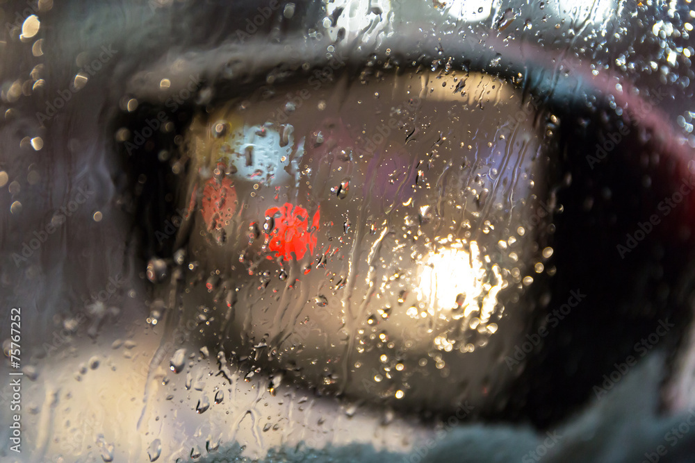 Fototapeta premium Blurry side mirror seen through the wet car window