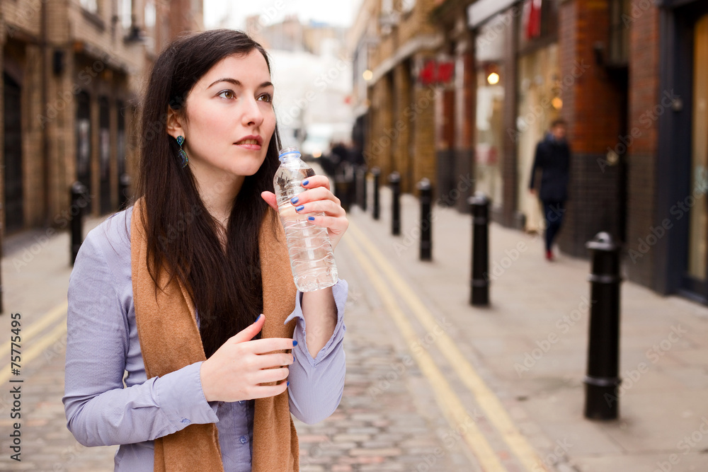 Fototapeta premium young woman drinking water in the street.