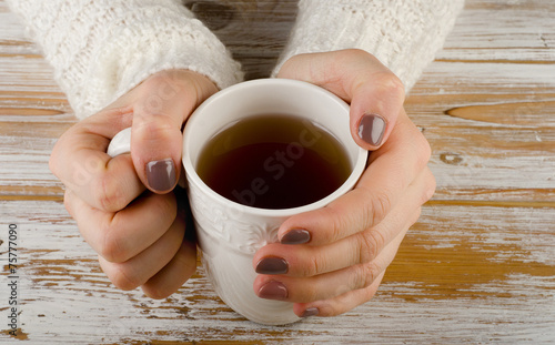 Woman holding tea cup over a wooden background