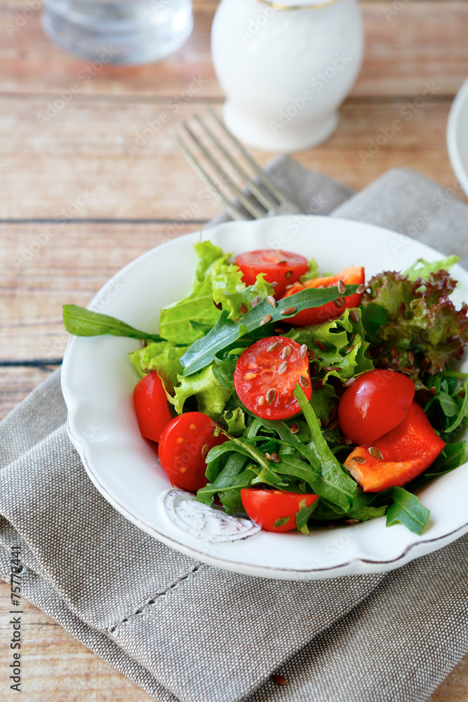 Fresh salad with tomatoes and arugula on a white plate