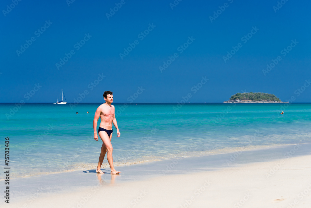 Young man walking out of the water in a tropical beach