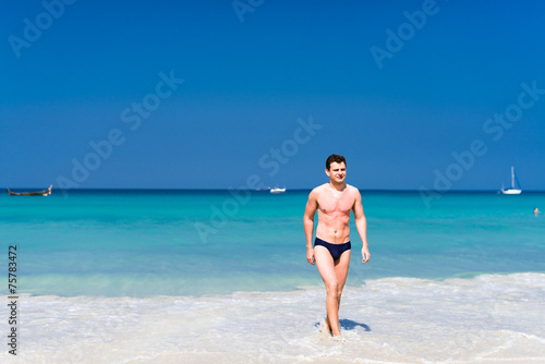 Young man walking out of the water in a tropical beach