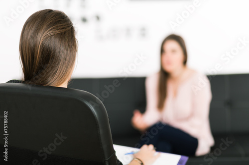 Female psychologist making notes during psychological therapy se