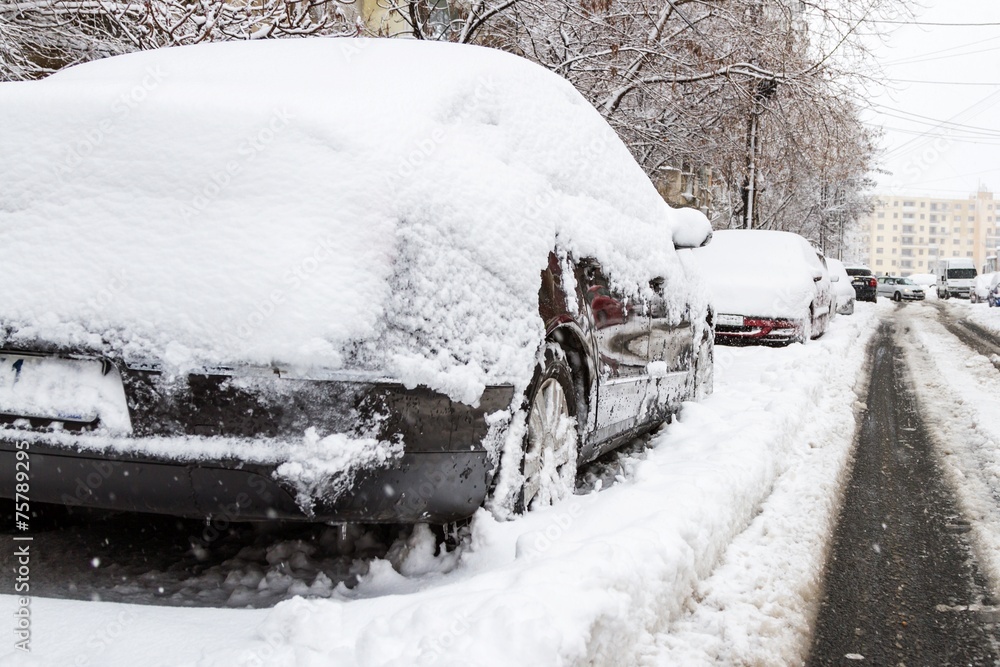 Car covered with snow in the parking after a snow storm Car covered with snow in the parking after a snow storm