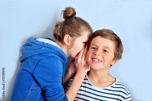 Quadro su tela Schwester flüstert Bruder etwas ins Ohr