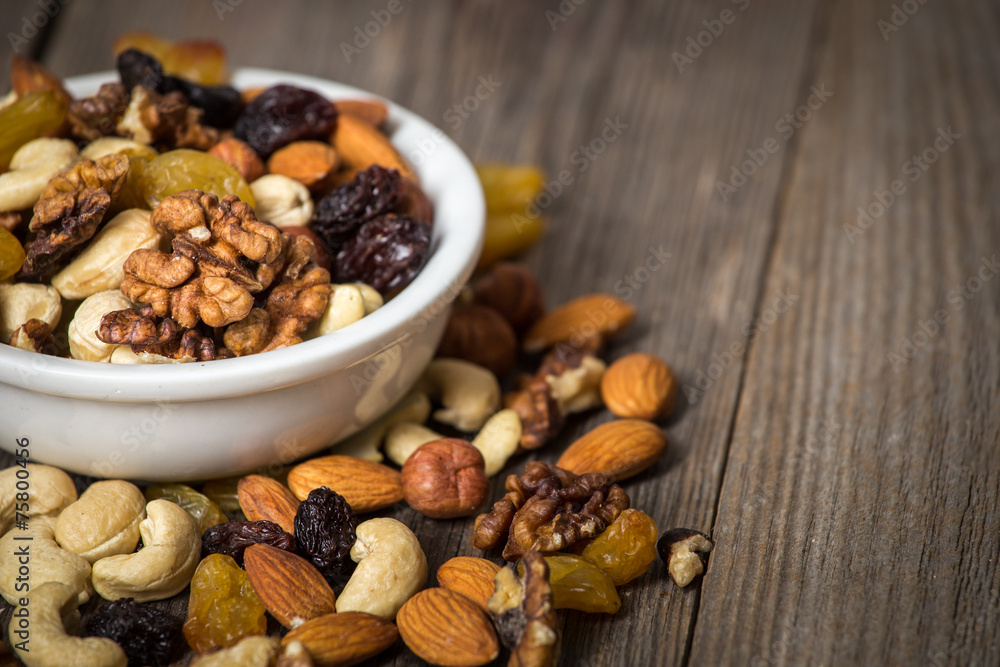 Assorted nuts in white bowl on wooden table. Assorted nuts in white bowl on wooden table.