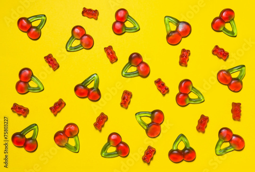 Gummy bears and cherry candies on a yellow background