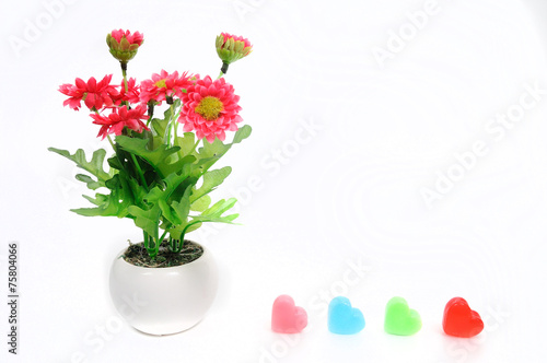 Red flowers in white flower pot with heart, artificially