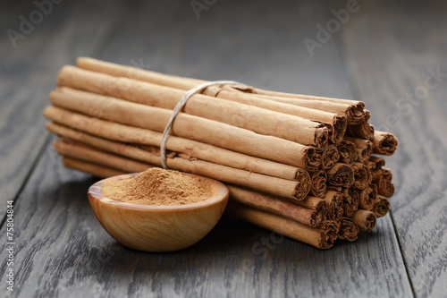 bunch of cinnamon sticks tied with twine and powder in bowl photo