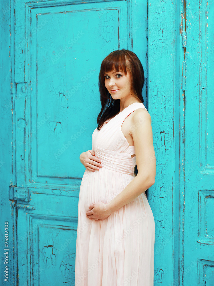 Fototapeta premium Lovely beautiful pregnant woman in dress against the colorful ba