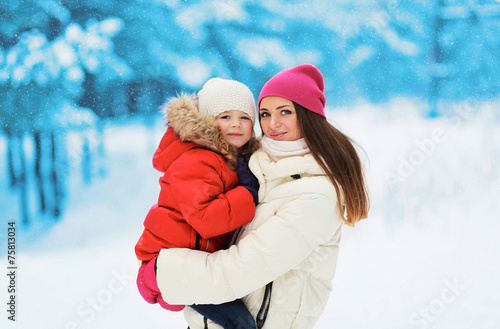 Happy mother and child together in snowy day against the snowfla photo