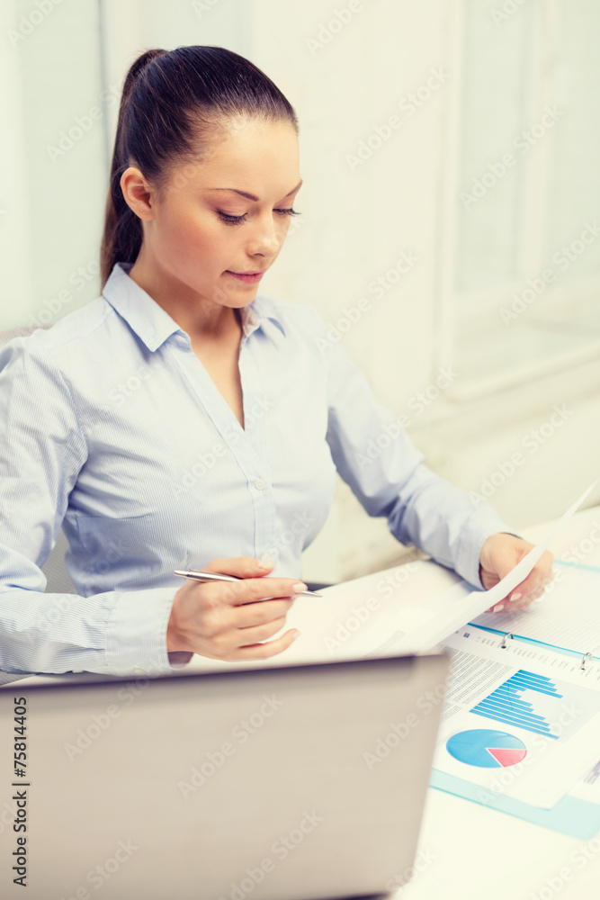 businesswoman with laptop and charts in office businesswoman with laptop and charts in office