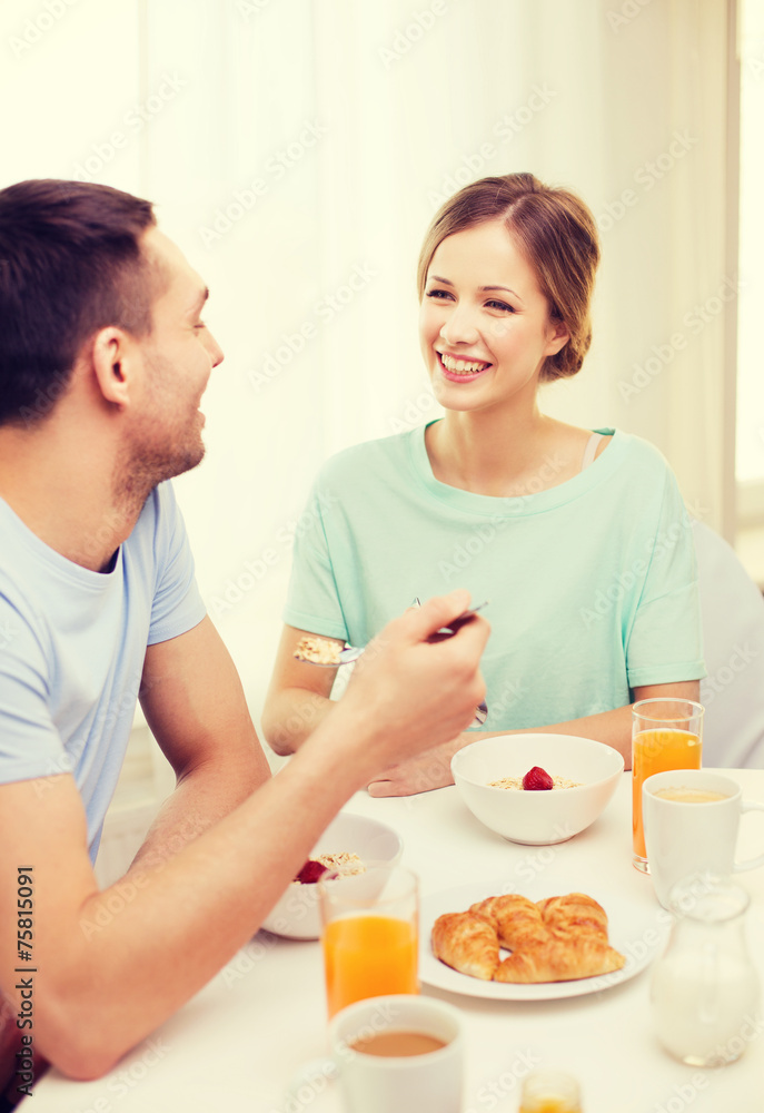 smiling couple having breakfast at home