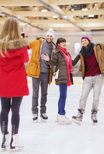 happy friends taking photo on skating rink