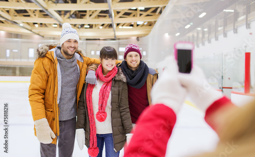 happy friends taking photo on skating rink © Syda Productions