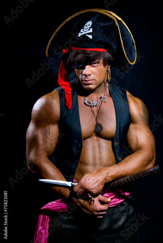 Portrait of a muscular pirate with a knife on a dark background