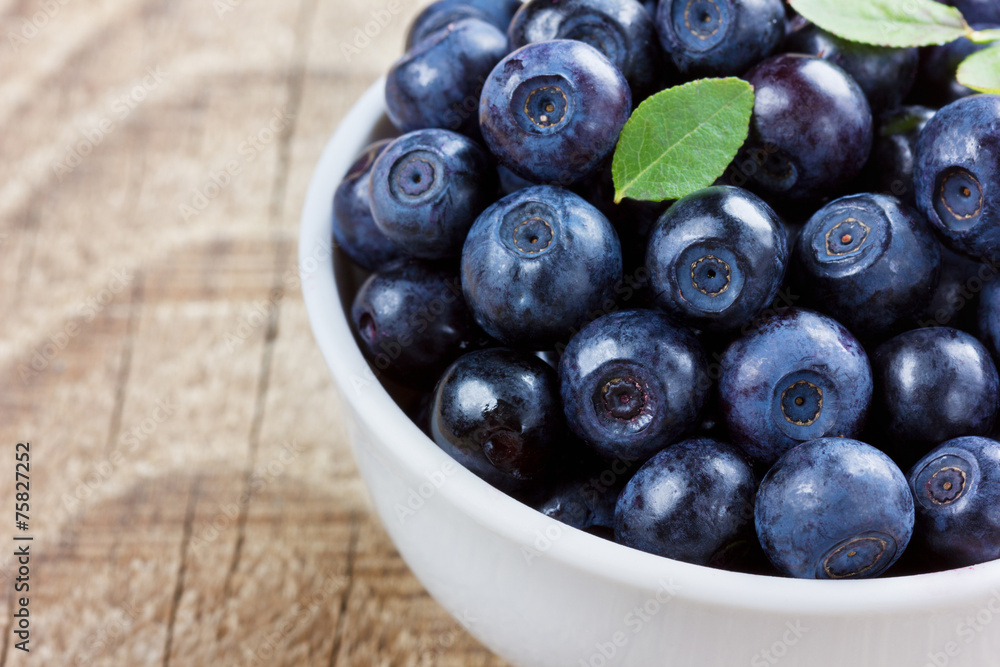 blueberries in the white bowl on a wood rustic background blueberries in the white bowl on a wood rustic background