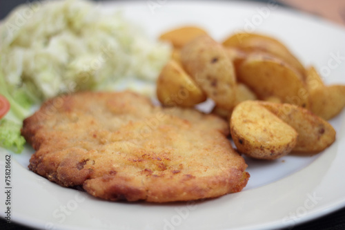 Wiener schnitzel with fried potato wedges and cabbage salad.