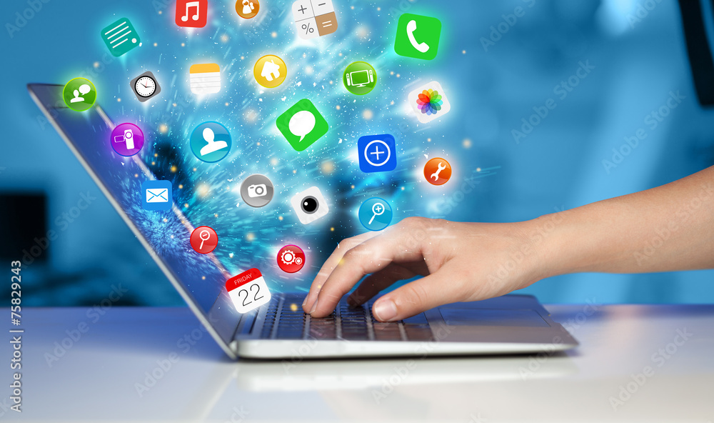 Hand pressing modern laptop with mobile app icons and symbols Hand pressing modern laptop with mobile app icons and symbols