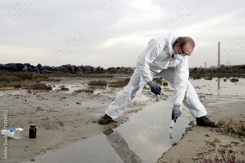 Worker in a protective suit examining pollution