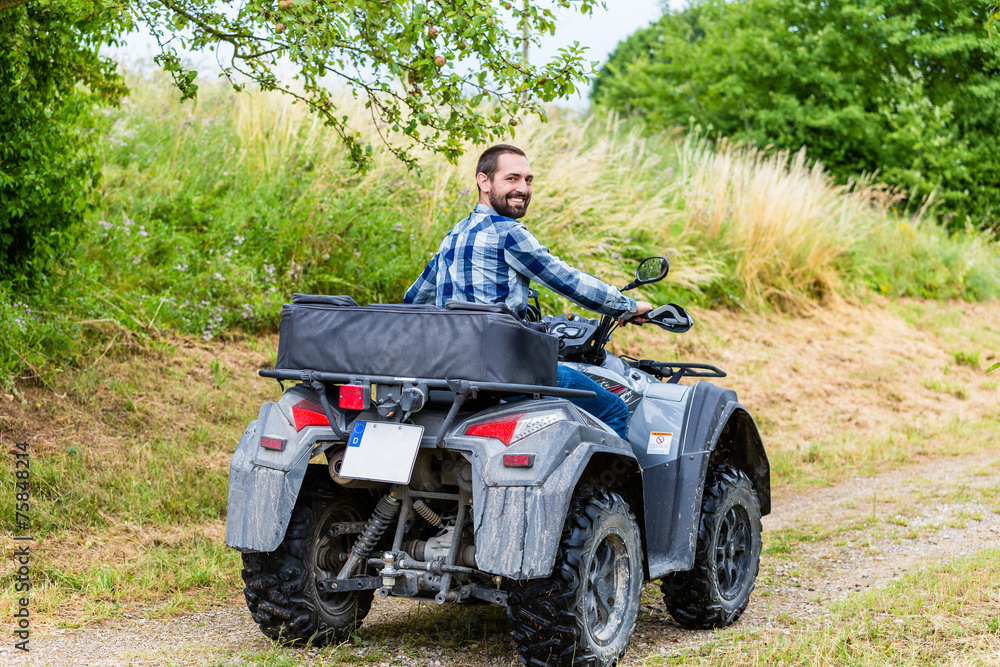 Mann fährt Off-Road mit Quad ATV durch Gelände 