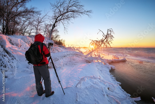 Photographer to take pictures on the river bank in winter