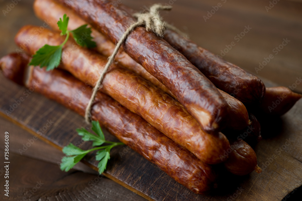 Stack of smoked sausages on a rustic chopping board, close-up Stack of smoked sausages on a rustic chopping board, close-up