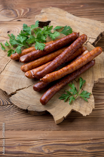 Stack of smoke-dried sausages with fresh parsley, studio shot