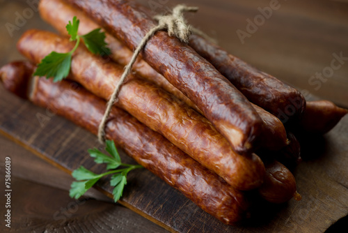 Stack of smoked sausages on a rustic chopping board, close-up