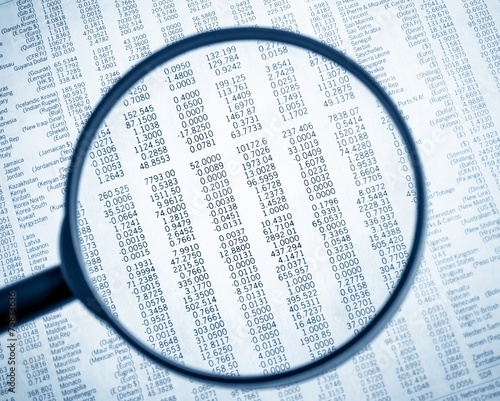 financial data see through lens of loupe on financial newspaper