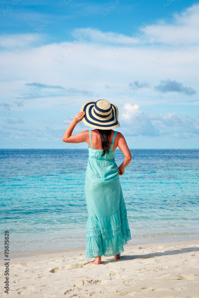 Girl walking along a tropical beach in the Maldives.