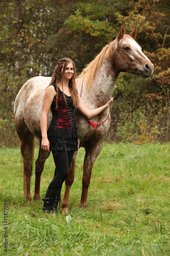 Beautiful girl with nice dress standing next to nice horse