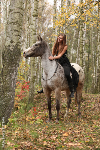 Young girl with appaloosa horse in autumn