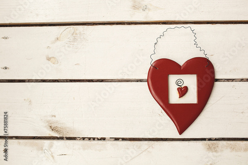 Valentines day toy heart hanging over white wooden background wi